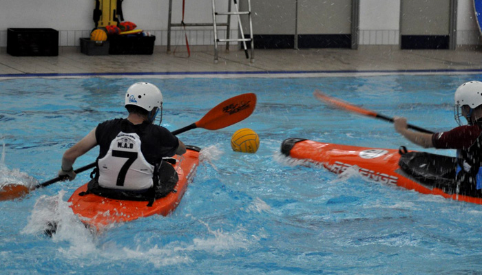 Canoe polo players chase the ball