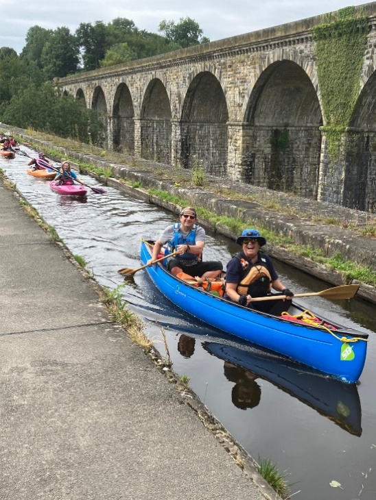 A group of people in canoes on a canal

Description automatically generated