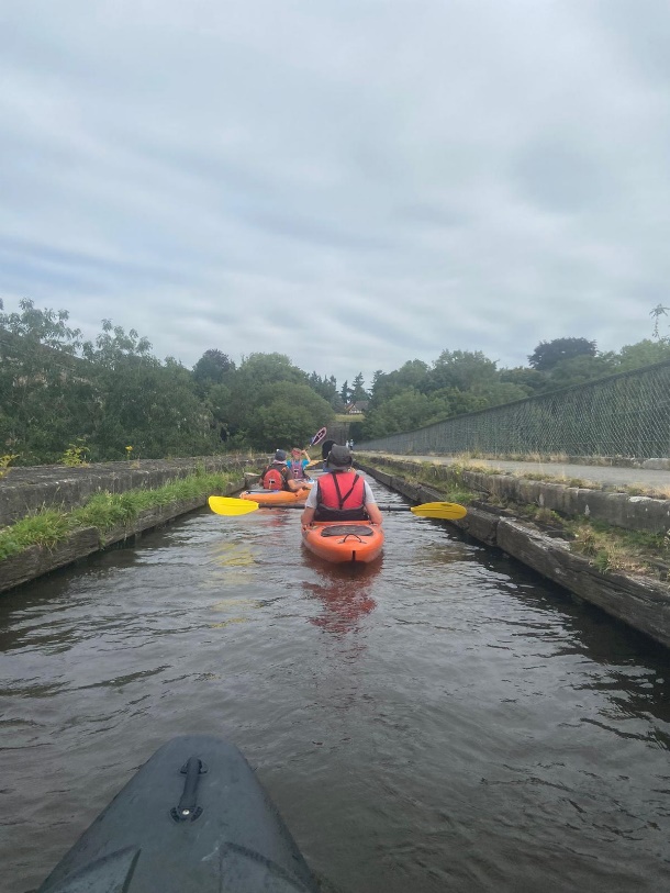 A group of people in kayaks on a canal

Description automatically generated