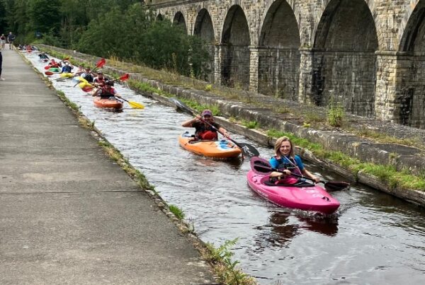 A group of people in kayaks on a canal Description automatically generated