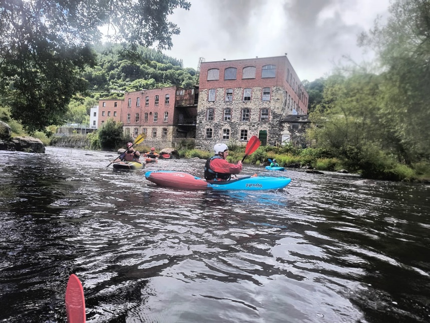 A group of people in kayaks on a river

Description automatically generated