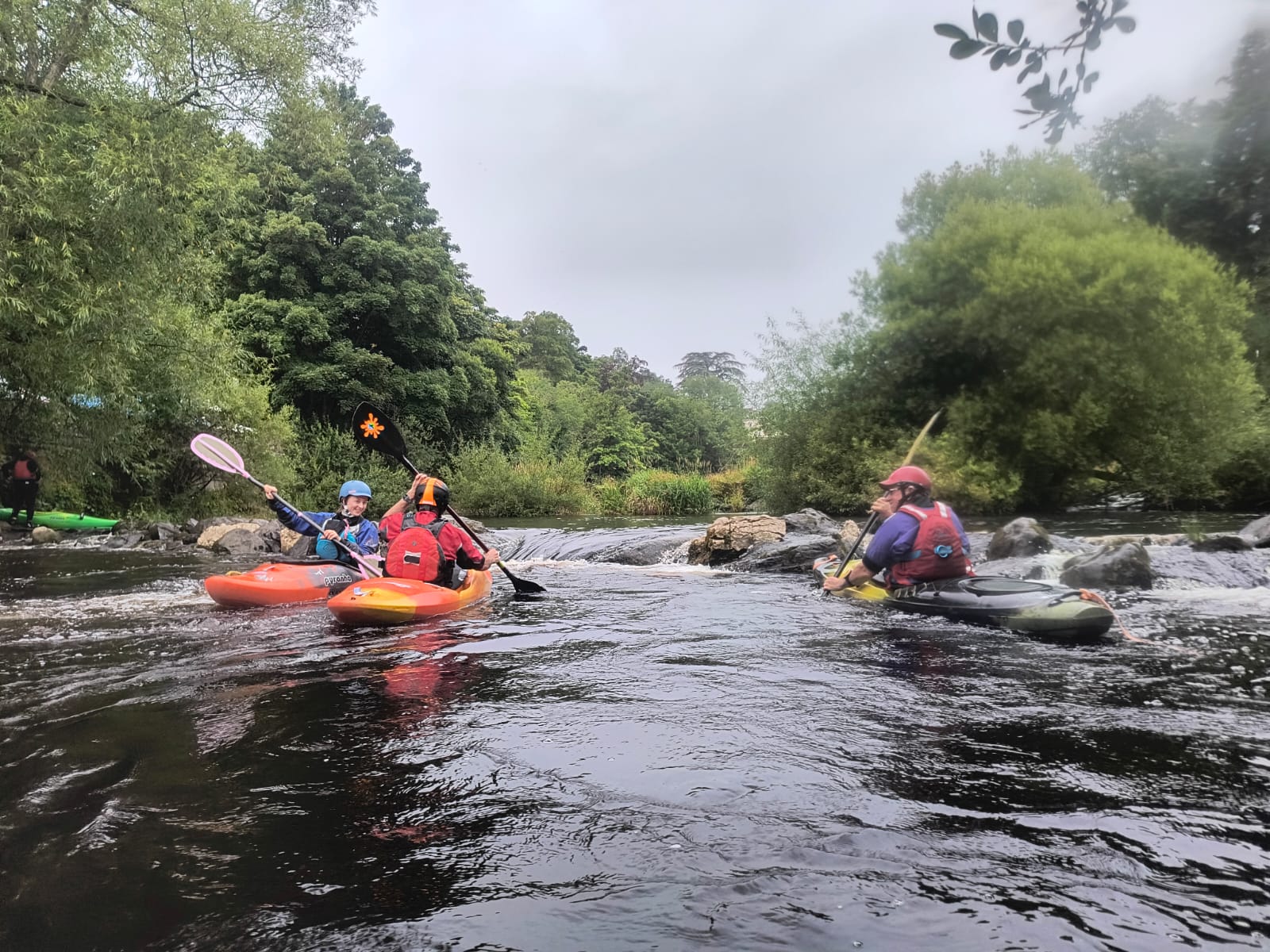 A group of people in kayaks on a river

Description automatically generated