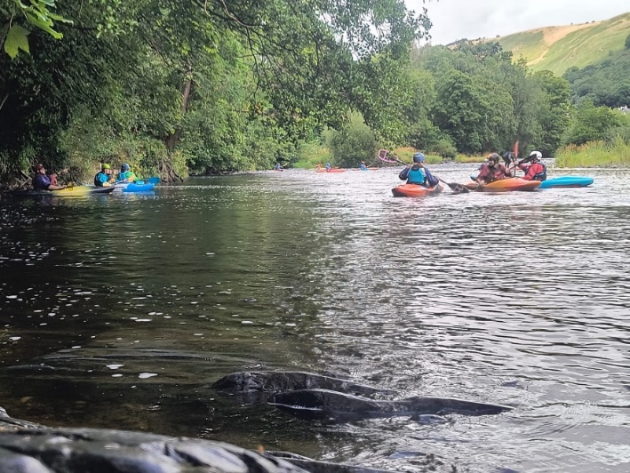 A group of people in kayaks on a river

Description automatically generated