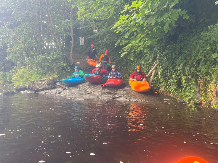 A group of people in kayaks on a river

Description automatically generated