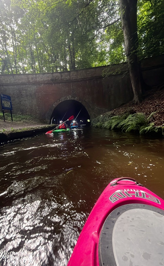 A group of people kayaking through a tunnel

Description automatically generated