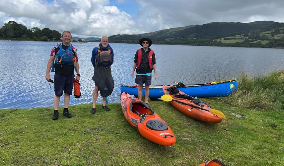 A group of people standing next to kayaks

Description automatically generated