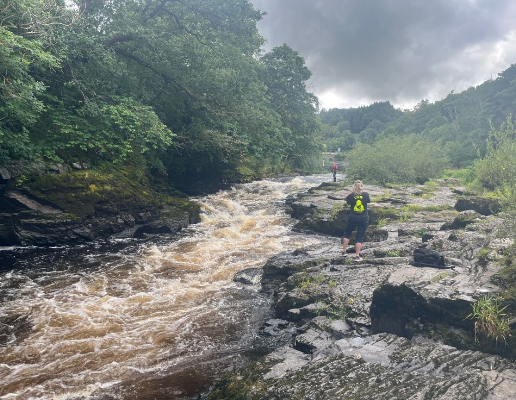 A person standing on rocks near a river

Description automatically generated