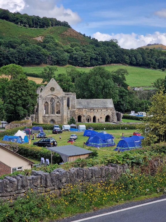 A stone building with blue tents in the background

Description automatically generated